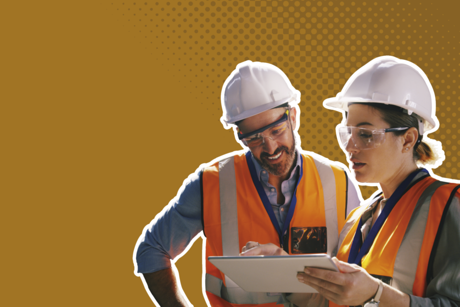2 building inspectors in hard hats and high vis jackets looking at a digital tablet