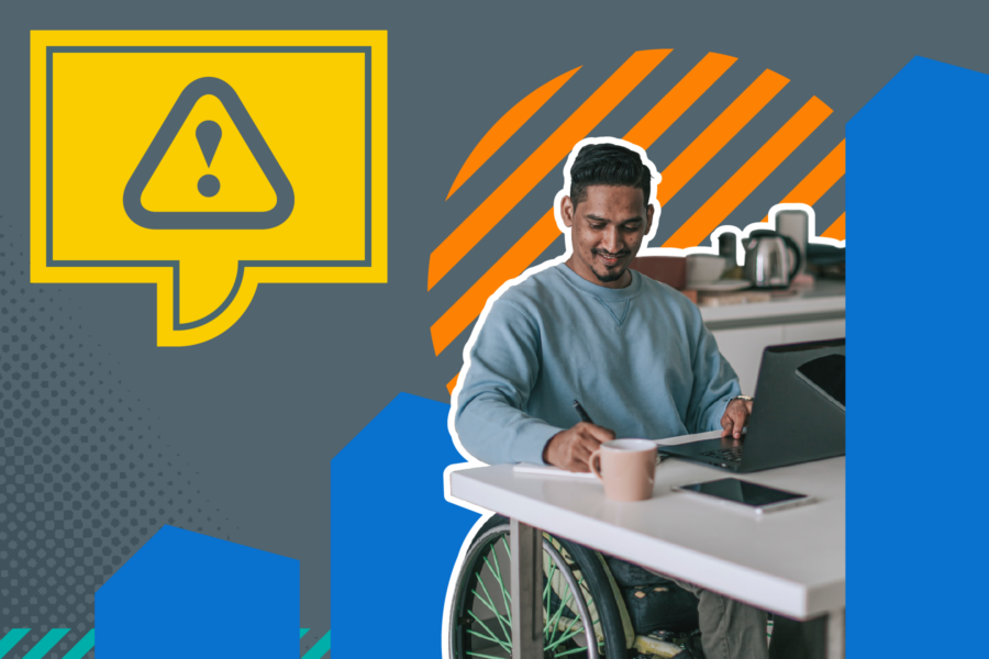 Man in a wheelchair working on a laptop in kitchen. And a yellow speech bubble with a warning sign in it..