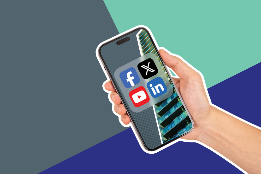 A hand holding a mobile phone showing four social media app icons. On a grey, dark blue and turquoise background.