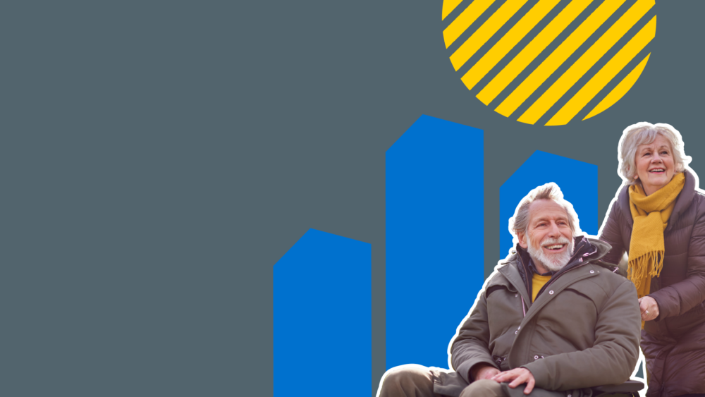 Older couple smiling, woman pushing man in wheelchair wearing winter coats and scarf.