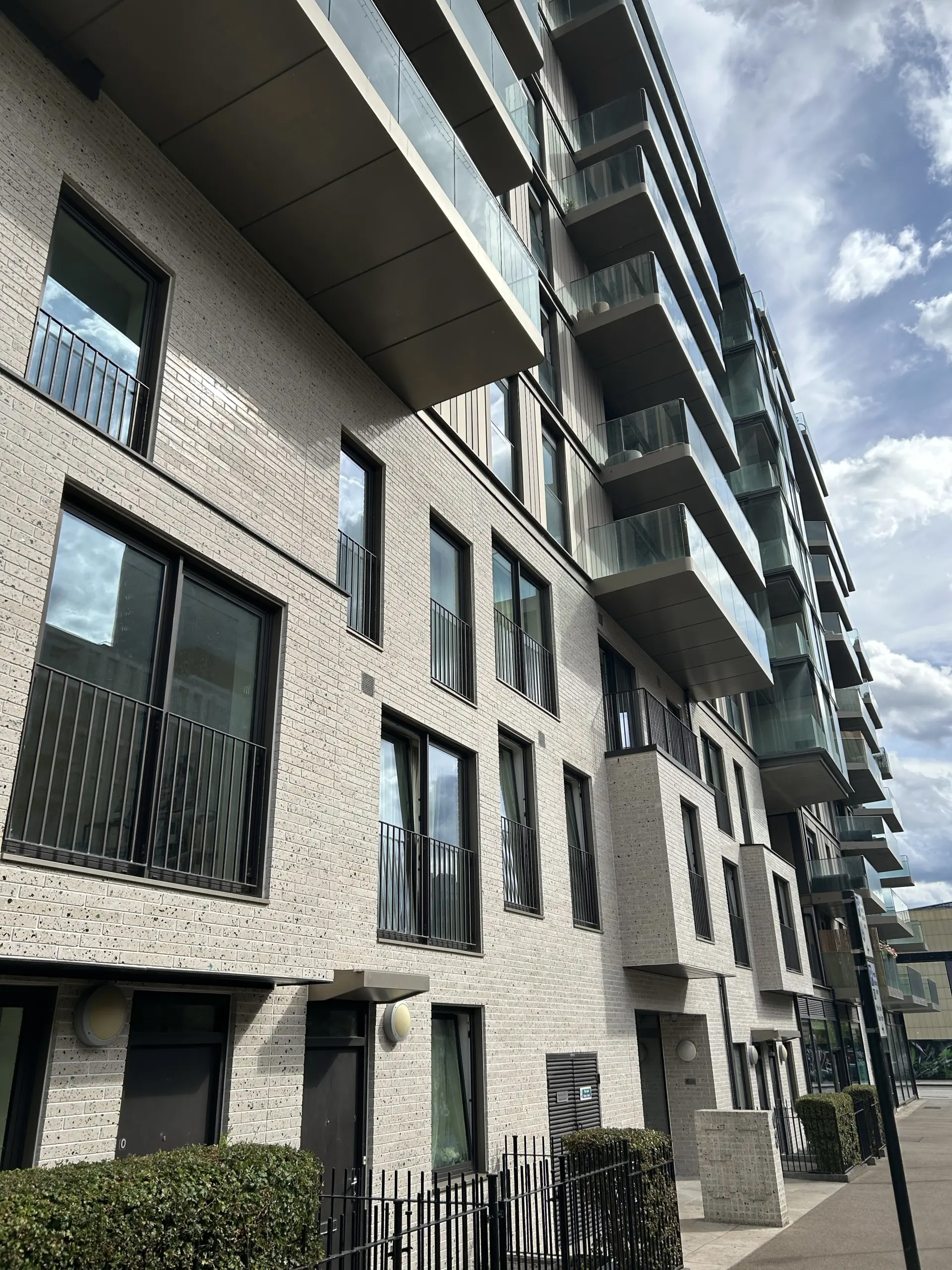 A grey bricked high-rise building with 9-10 floors with flats having balconies.